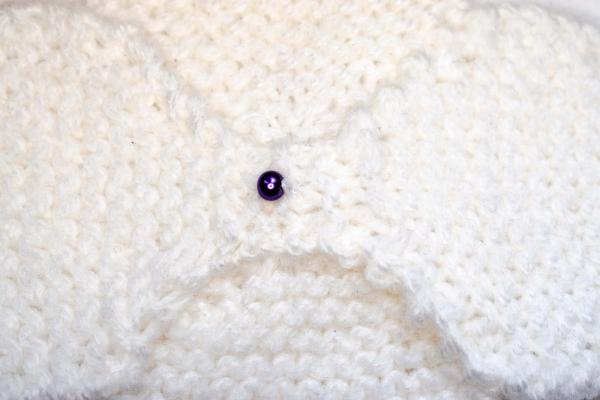 Hand knitted brooch in white with purple pearl